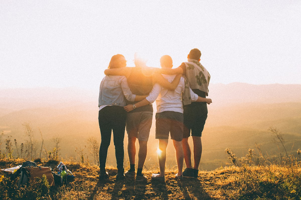 Personas abrazadas contemplando un paisaje al atardecer